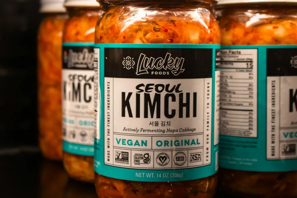 Jars of kimchi lined up on a dark surface