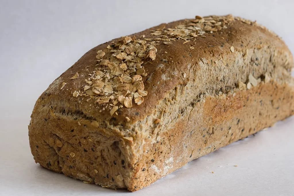 A rustic loaf of whole grain bread on a light surface