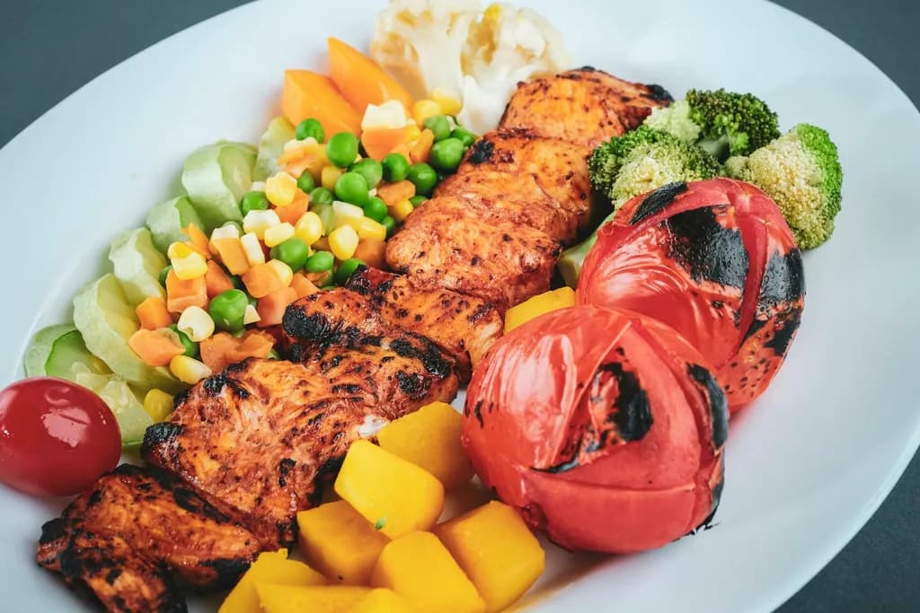 A cooked meal of fish and vegetables on a white plate